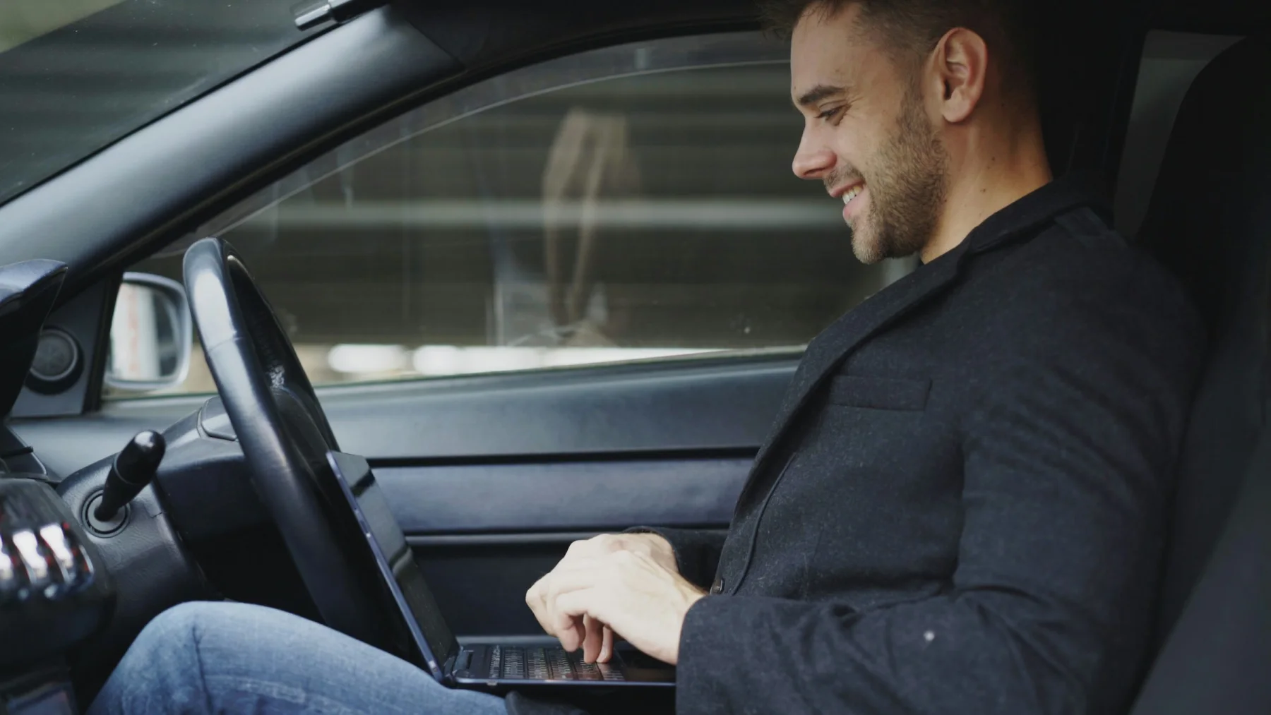 Man researching cars online on a laptop while parked